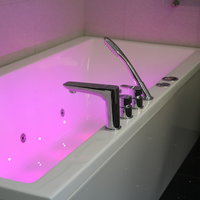 Eine weiße, kantige Badewanne mit LED-Beleuchtung